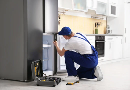 Technician examining a refrigerator in a bright residential kitchen