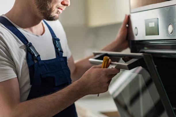 Technician checking an oven control panel with a hand tool